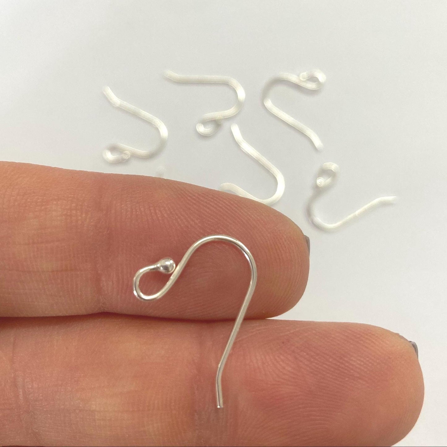 925 sterling Silver earring hooks on a finger with a white background
