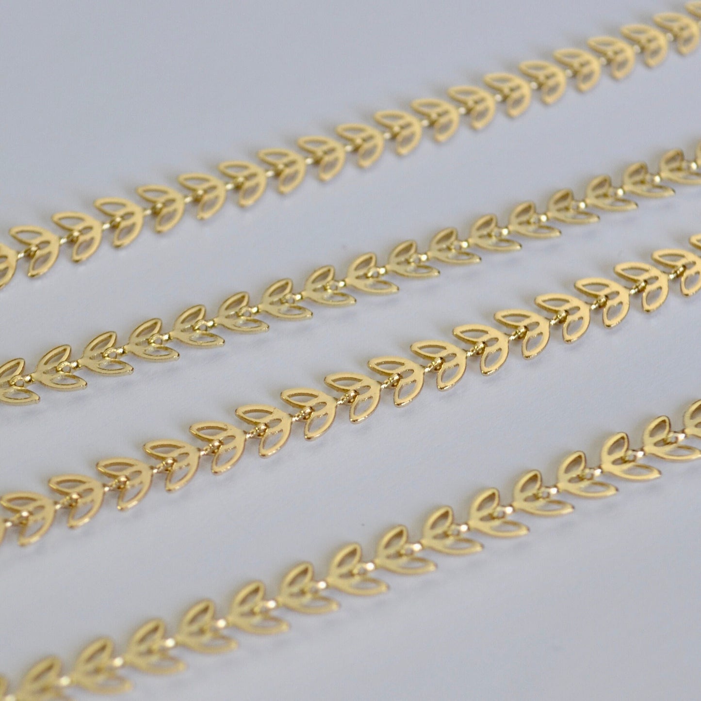 Gold chain with leaf design on a light gray background