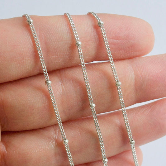 Sterling Silver satellite chain on a hand against a light background