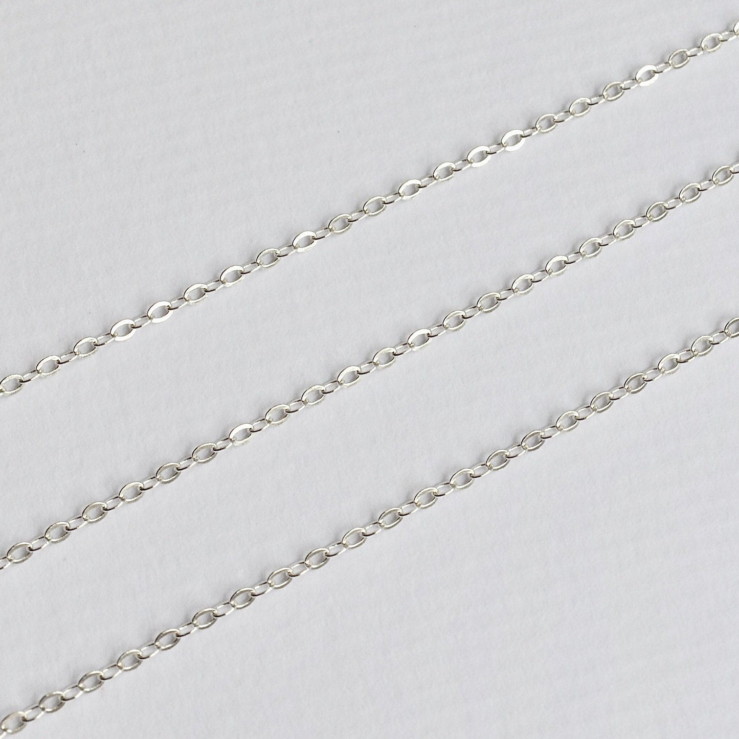 Silver cable chain on a light gray background