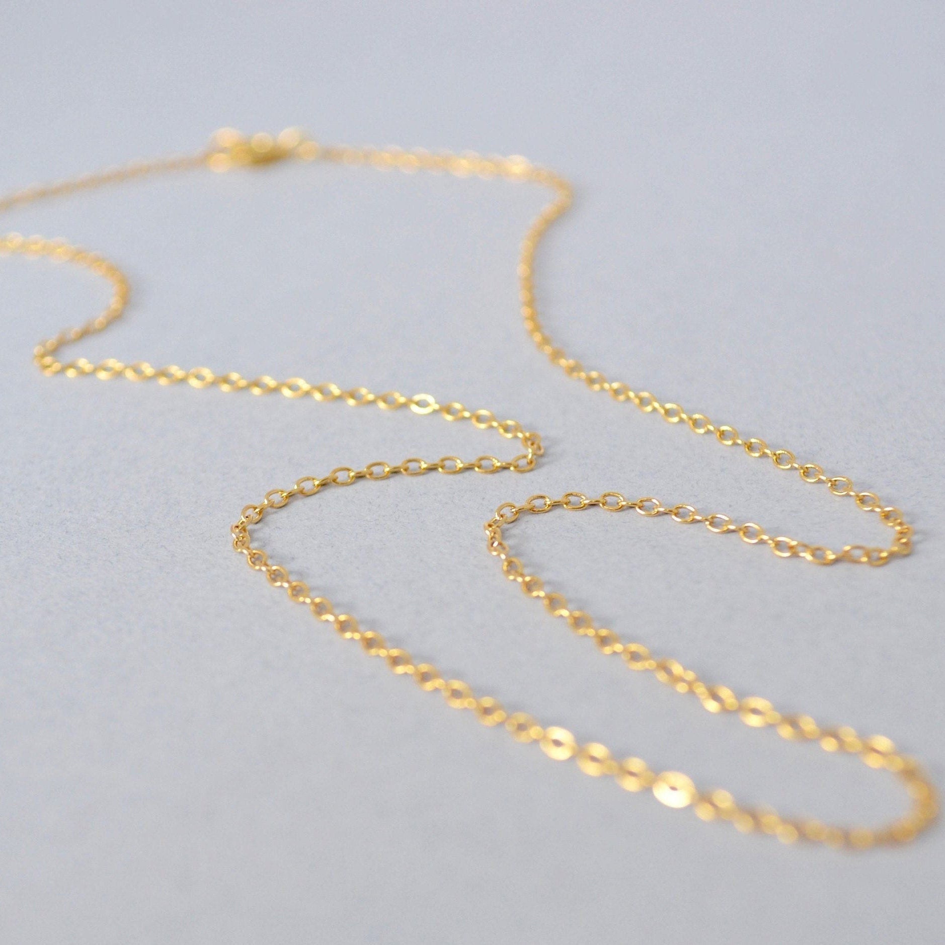 Gold chain necklace on a light gray background