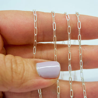 Silver chain held between fingers with a blurred background