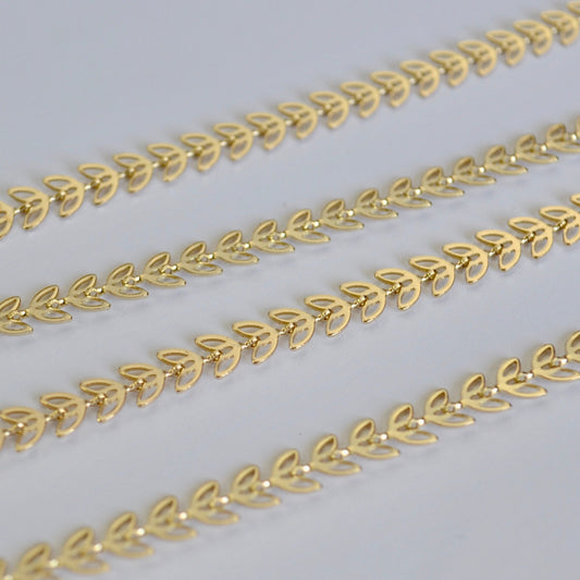 Gold chain with leaf design on a light gray background