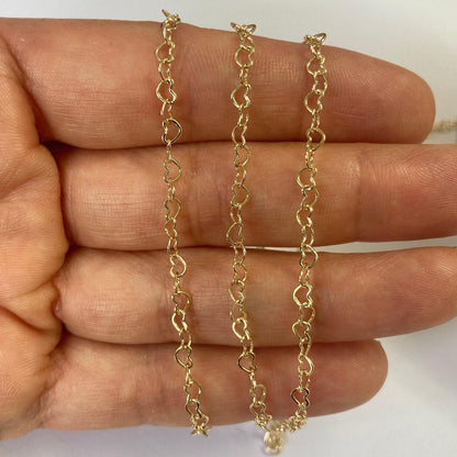 Gold filled extender heart chain held between fingers on a white background