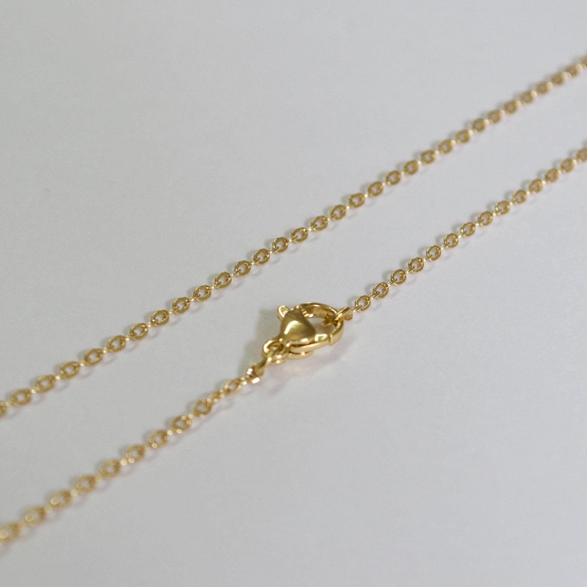 Gold chain necklace on a light gray background