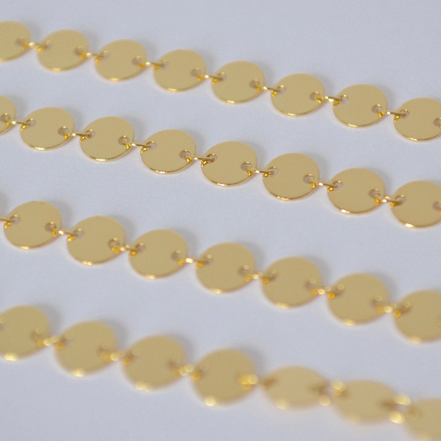Gold filled sequin chain close up on a white background