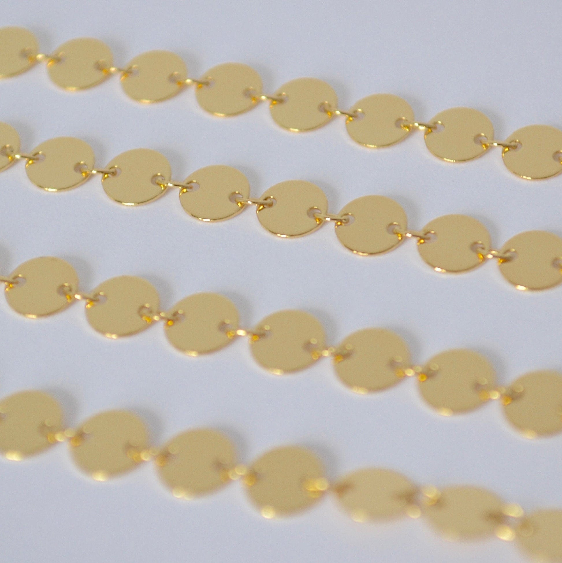 Gold filled sequin chain close up on a white background