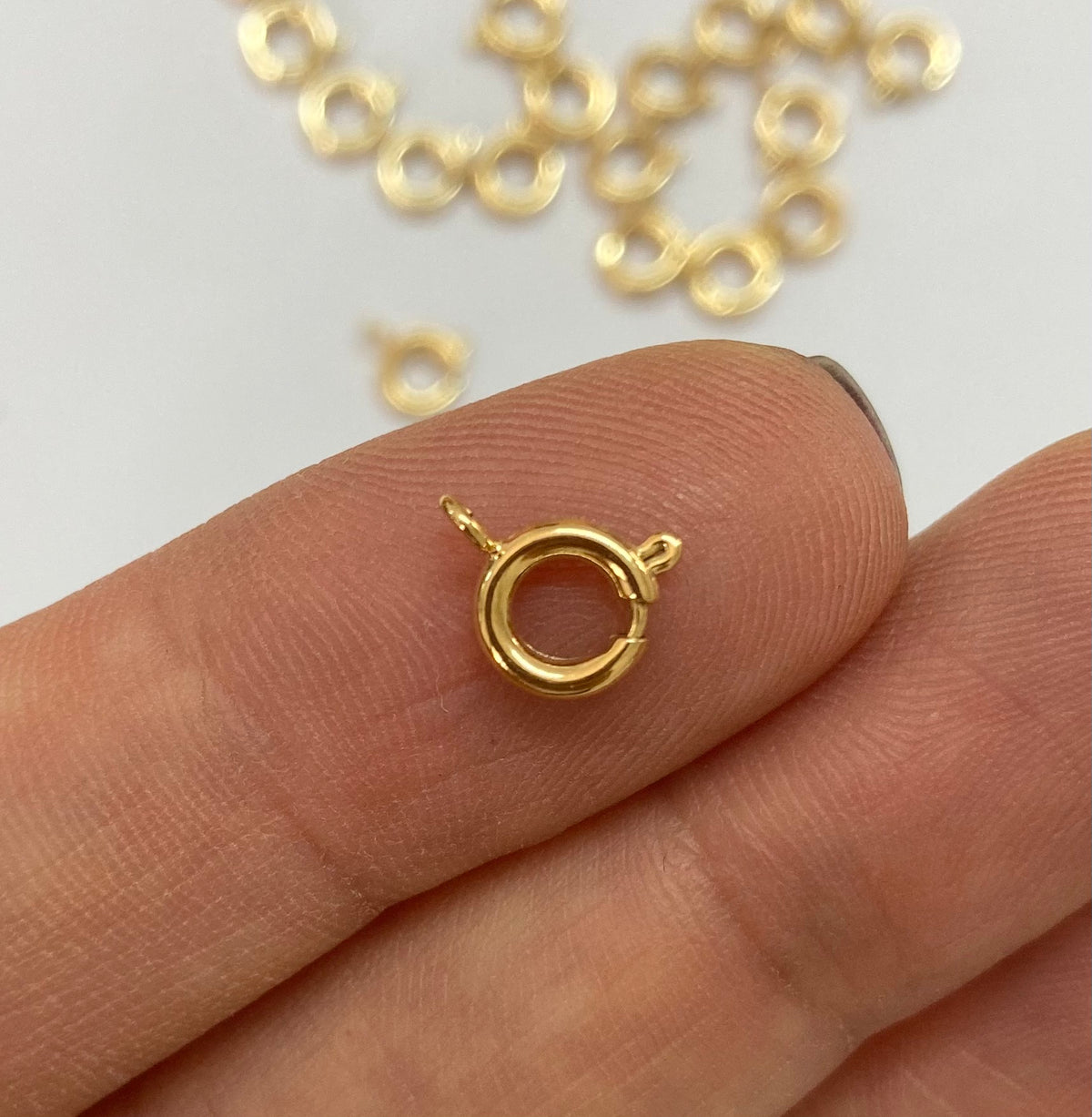A small gold filled spring ring clasp held between fingers