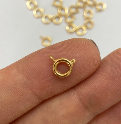 A small gold filled spring ring clasp held between fingers