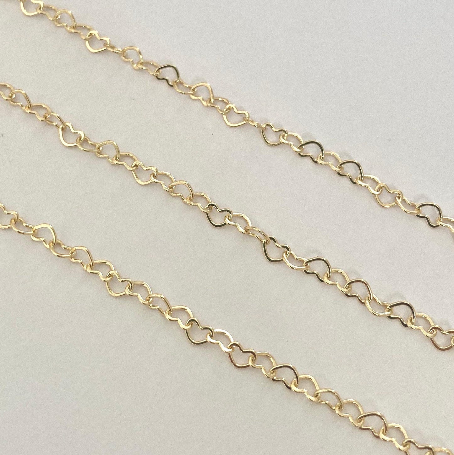 Gold heart extender chain on a light gray background