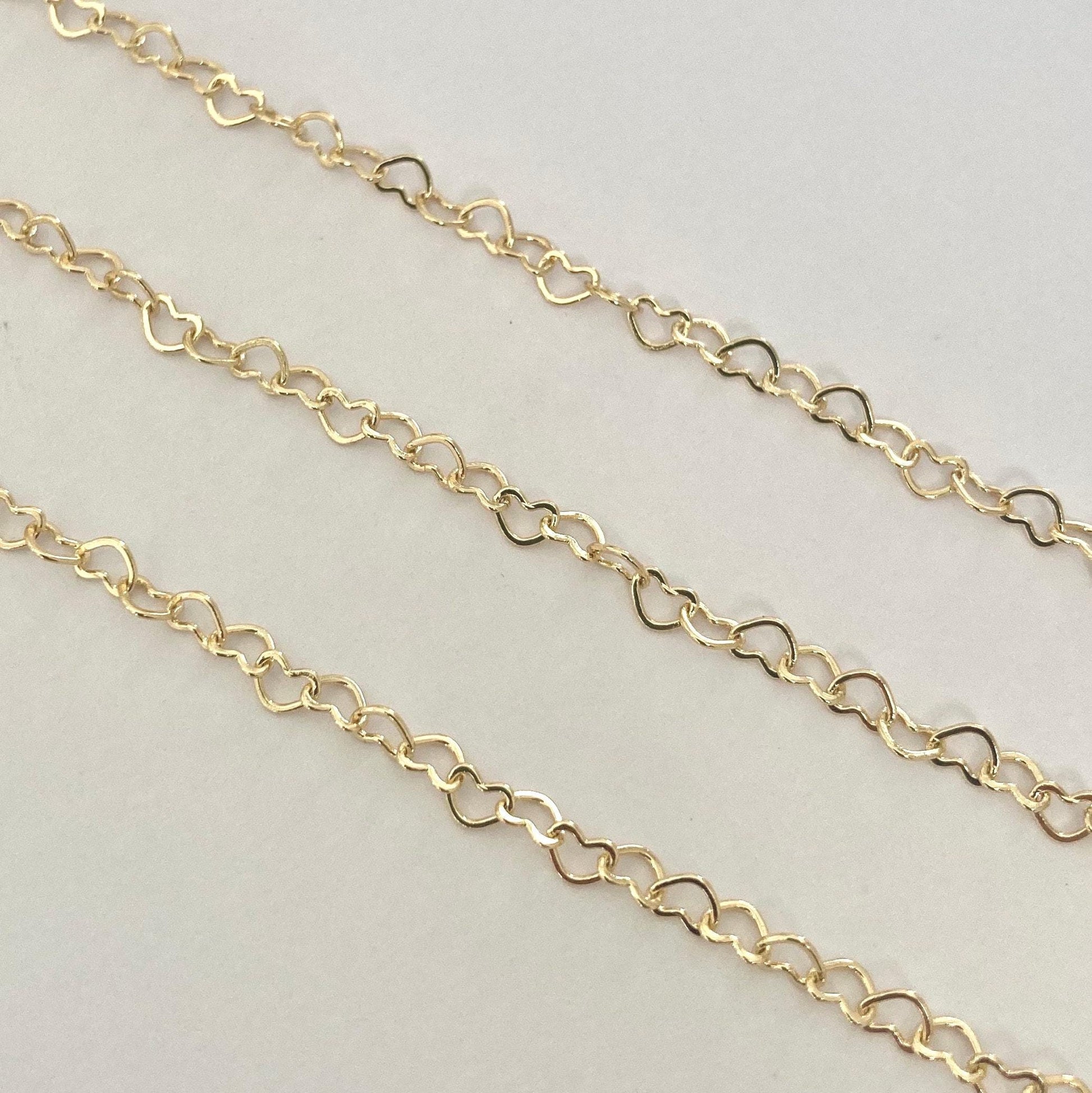 Gold heart extender chain on a light gray background