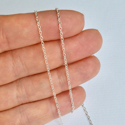 Silver cable chain held between fingers against a light background
