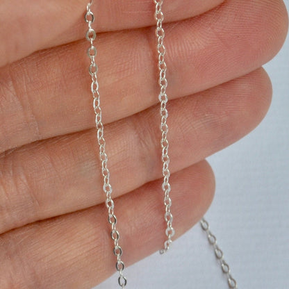 925 sterling Silver cable chain held between fingers against a neutral background
