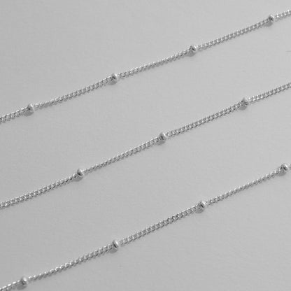 Silver satellite chain necklaces on a light gray background
