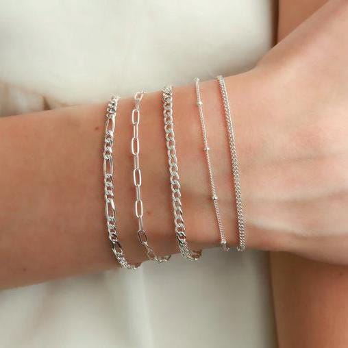 Silver bracelets on a wrist against a neutral background