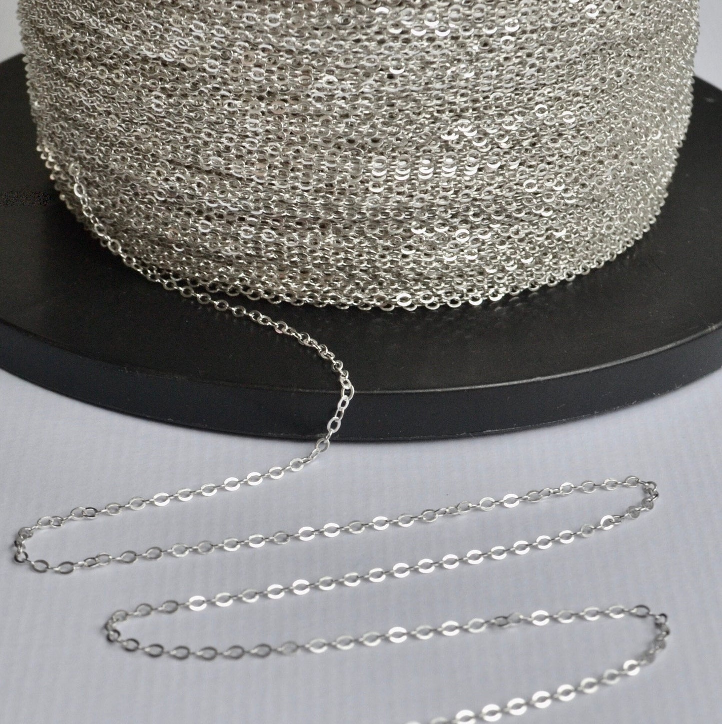 Sterling Silver cable chain on a spool with a black background