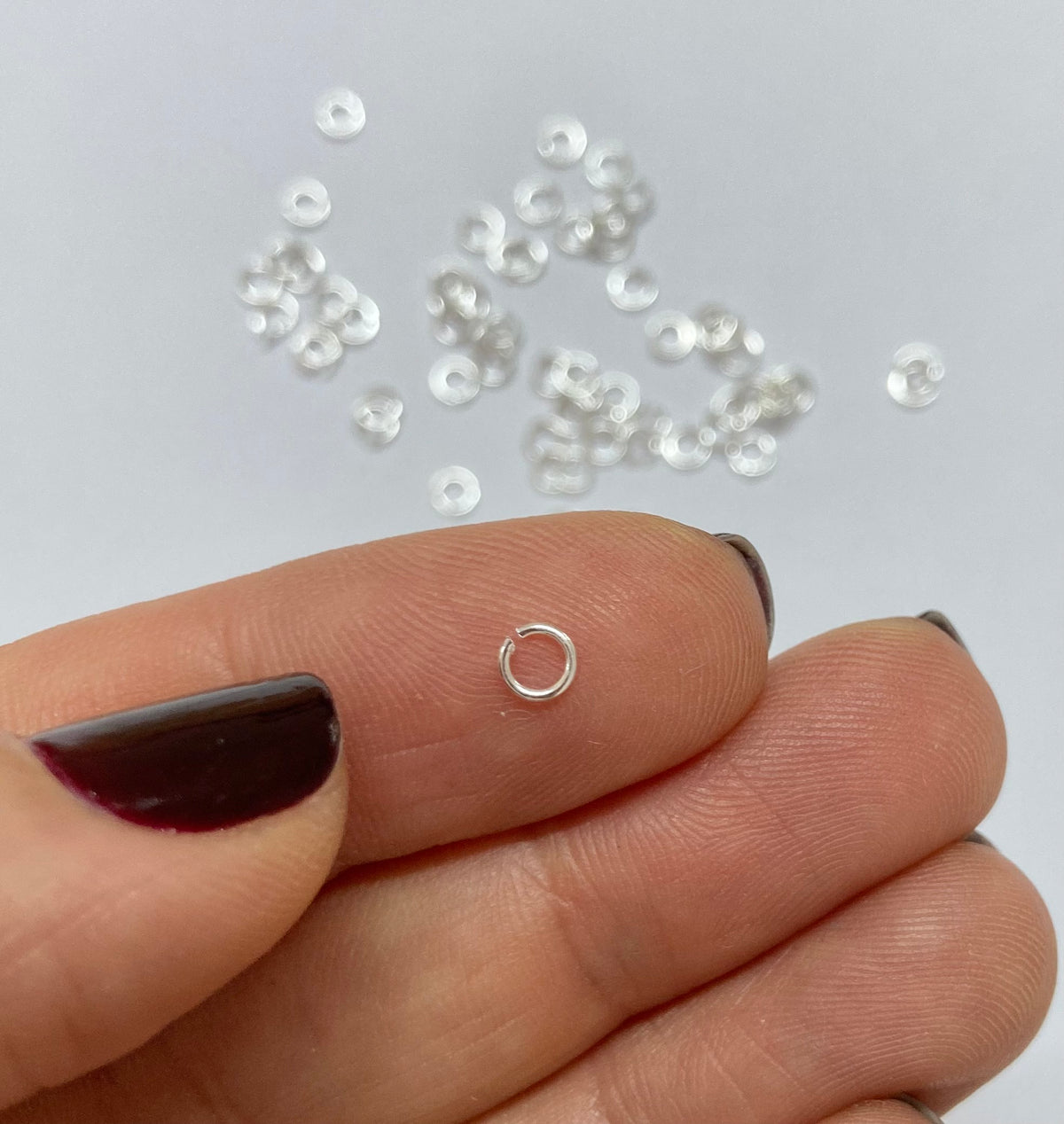 Tiny sterling silver jump ring on a finger