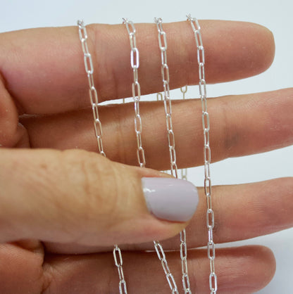 Silver paper clip chain held between fingers against a white background