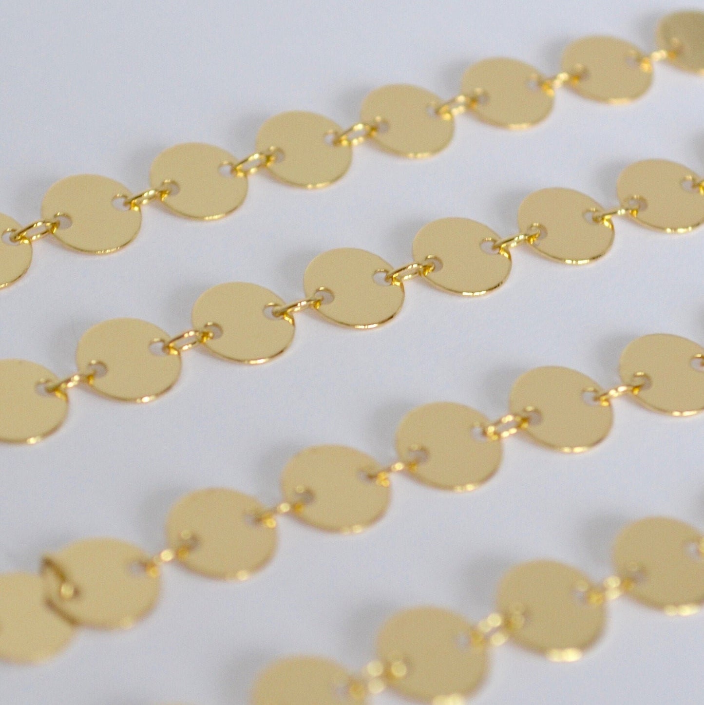 Close-up of a gold coin chain on a light gray background