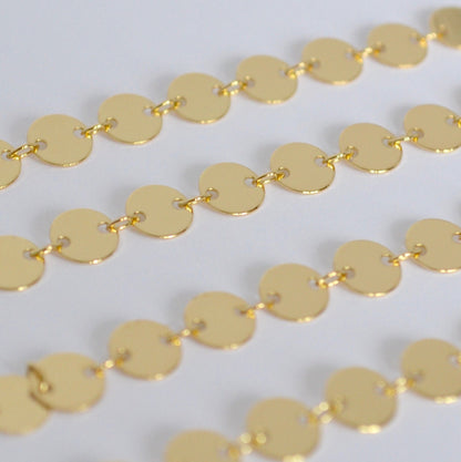 Close-up of a gold coin chain on a light gray background